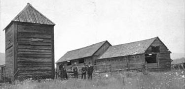 Fort Colvile. Bastion and building behind unidentified men.